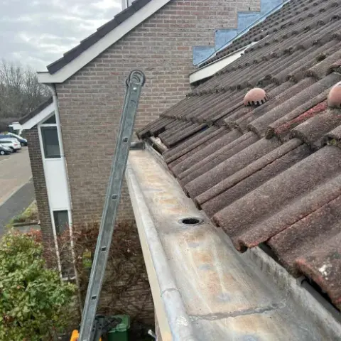 Schoongemaakte zinken dakgoot met vrijgemaakte regenwaterafvoer