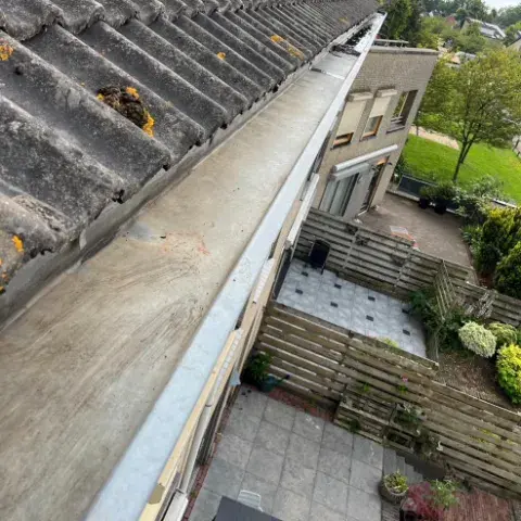 Schoongemaakte zinken dakgoot langs het schuine dak van een woning